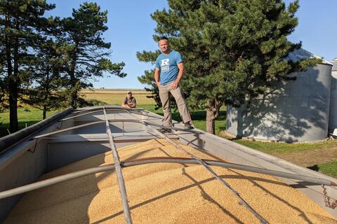 Matt Riggs stands on top of a semi full of grain with his brother Darin in the background.